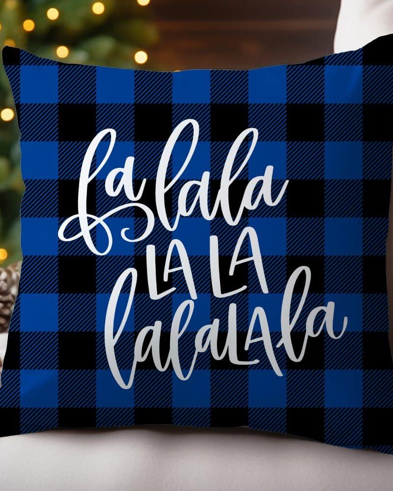 Blue and black buffalo plaid throw pillow with the words "fa la la la la la la" in white script.