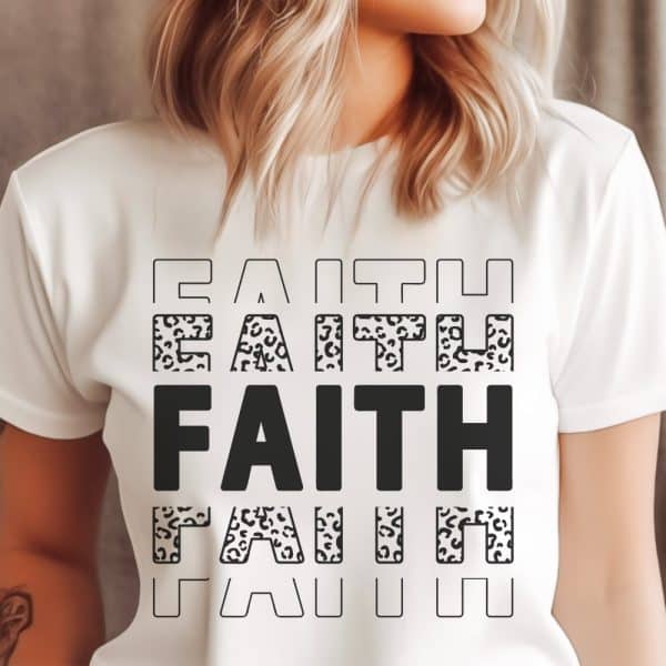 White T-Shirt With The Word Faith Repeated In A Layered Design. Some Letters Have A Leopard Print Pattern.
