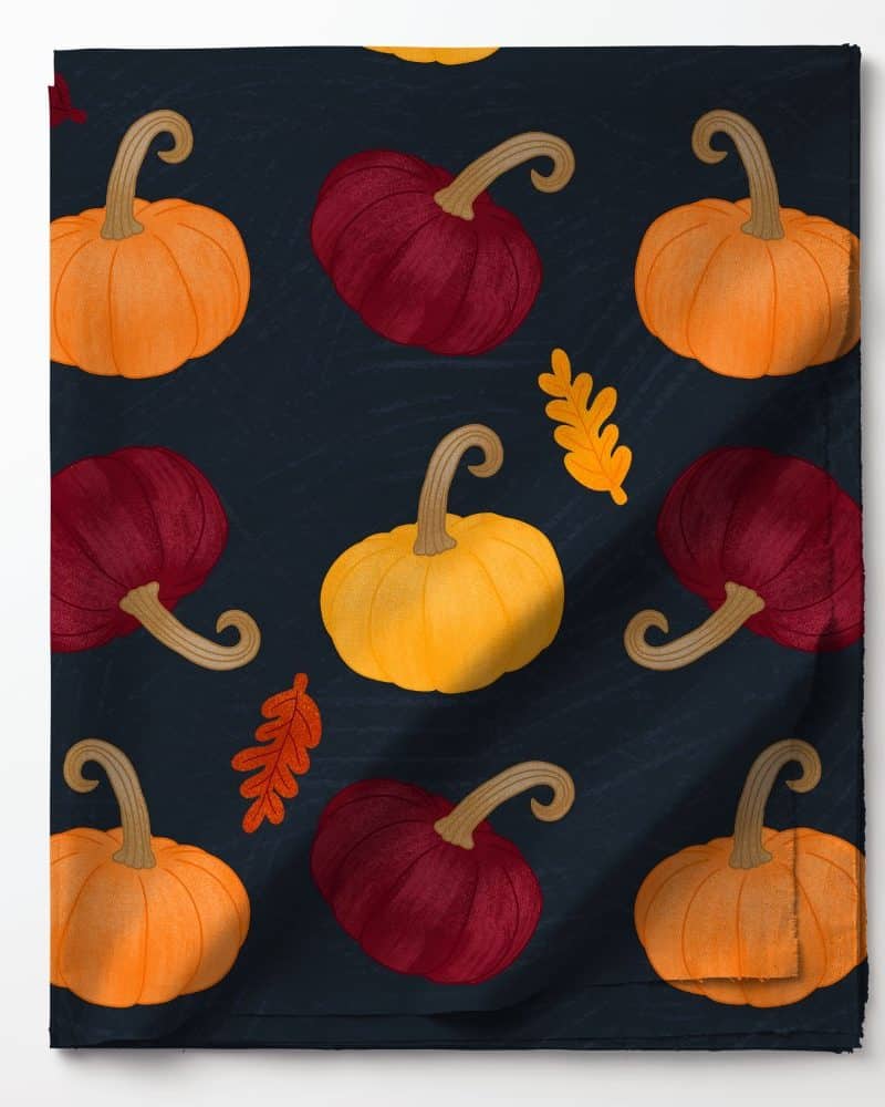 Dark fabric with a repeating pattern of orange, yellow, and burgundy pumpkins and autumn leaves.