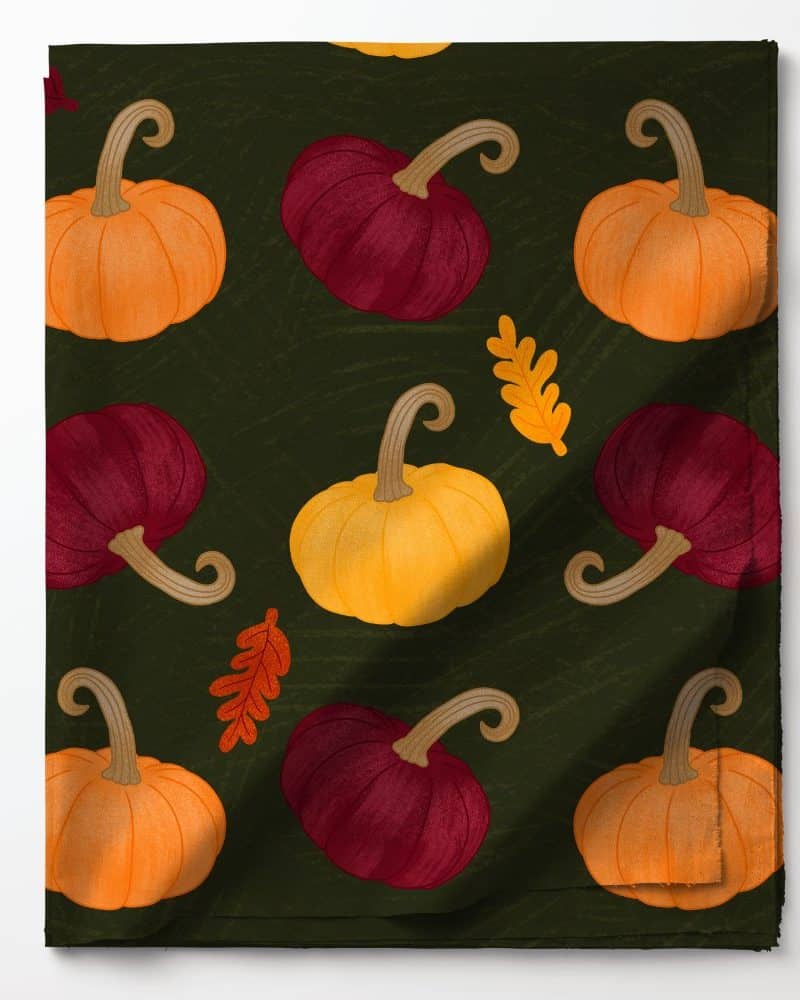 Dark green fabric with a repeating pattern of orange, yellow, and maroon pumpkins and autumn leaves.