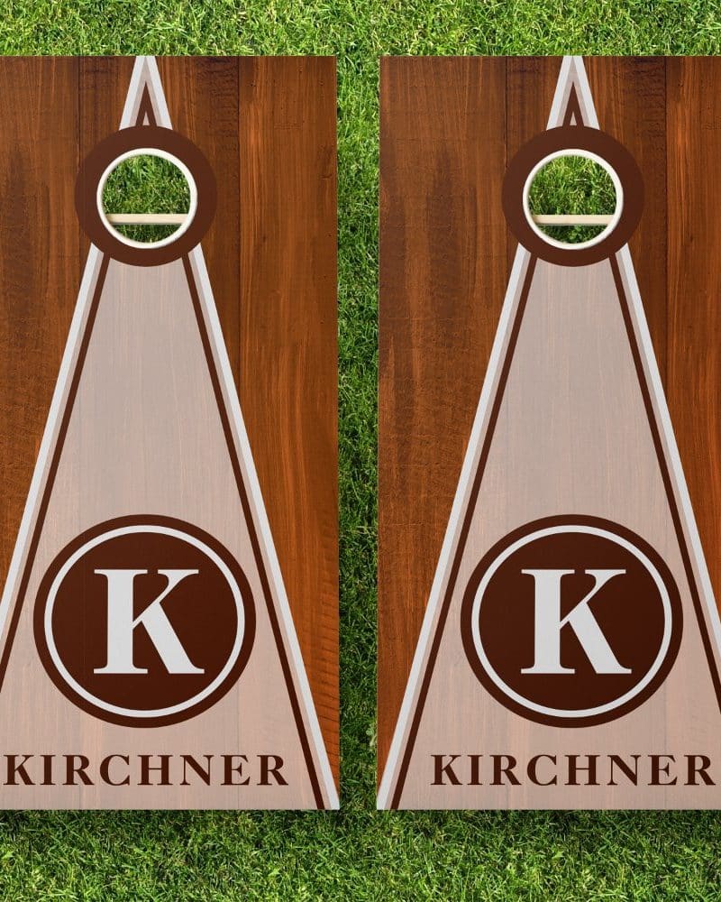 Pair of personalized cornhole boards with a brown wood grain finish, off-white triangle design, and the initial K in a brown circle, along with the last name Kirchner.