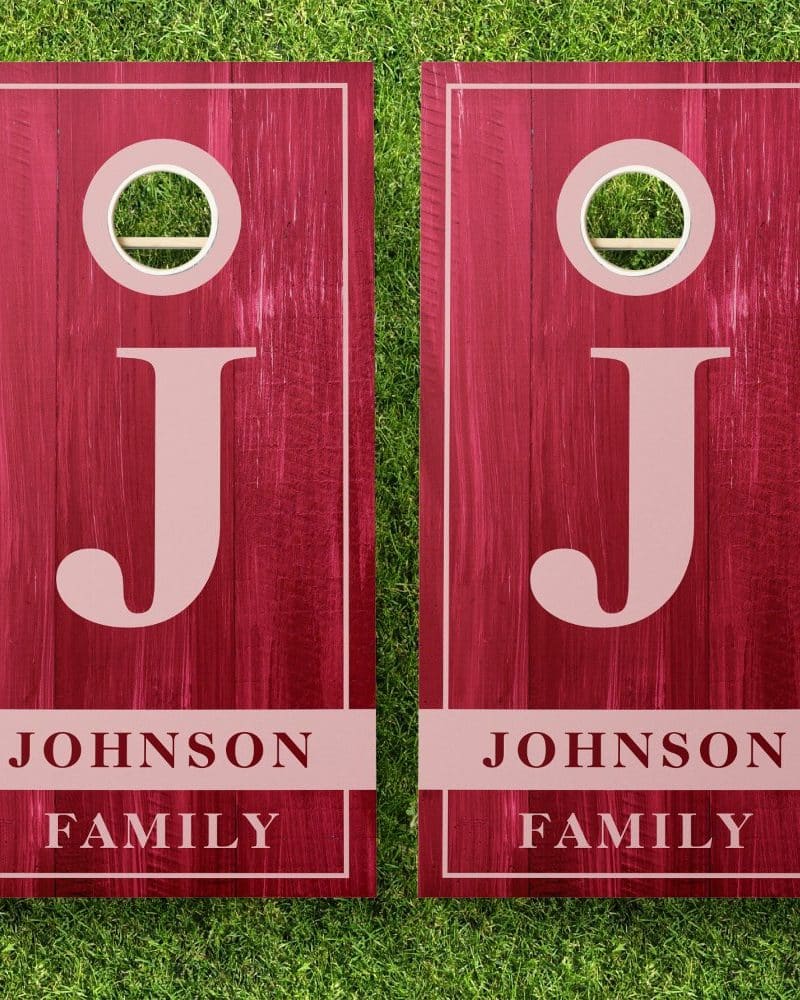 Two dark red personalized cornhole boards with the initial J and Johnson Family displayed.