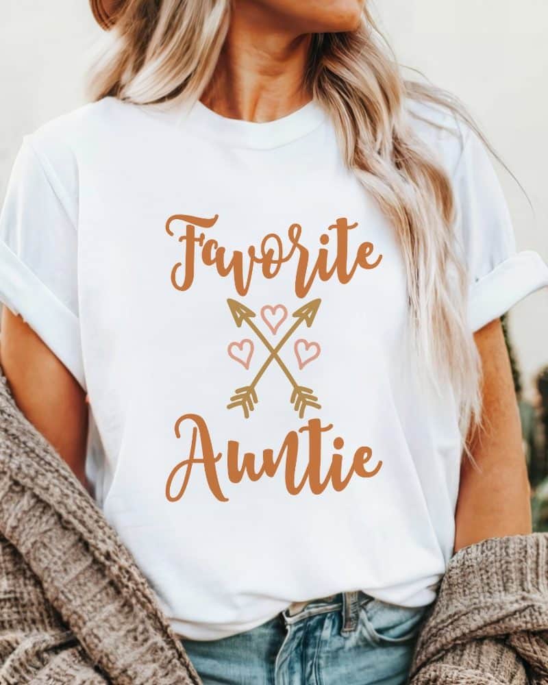 White t-shirt with the text Favorite Auntie in orange lettering, accented with a design of crossed arrows and hearts.