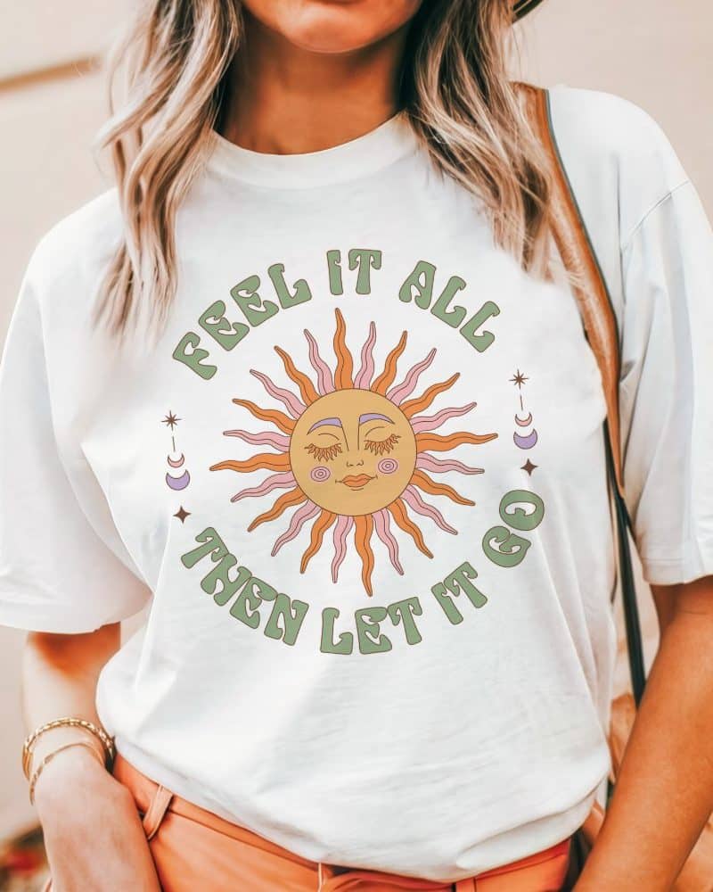 White t-shirt featuring a sun with a face and the text Feel it all then let it go.