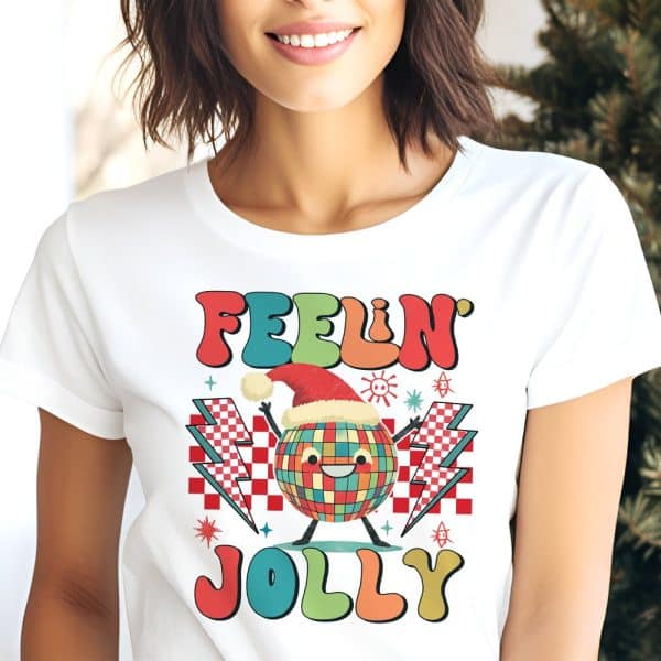 White T-Shirt Featuring A Retro-Style Design With A Smiling Disco Ball Wearing A Santa Hat, Surrounded By Lightning Bolts And The Text Feeling Jolly.