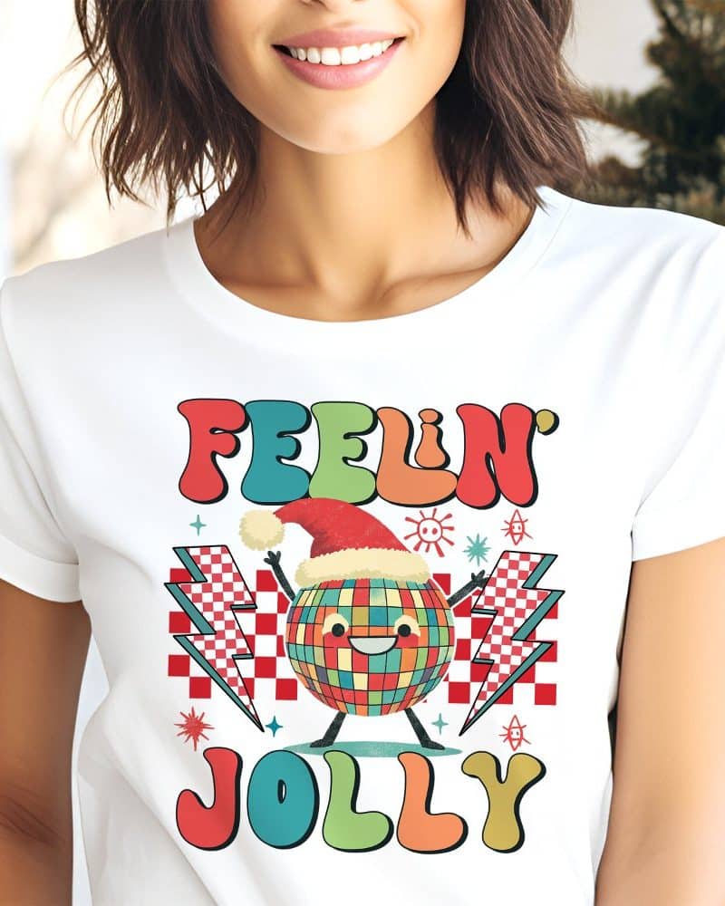 White t-shirt featuring a retro-style design with a smiling disco ball wearing a Santa hat, surrounded by lightning bolts and the text Feeling Jolly.