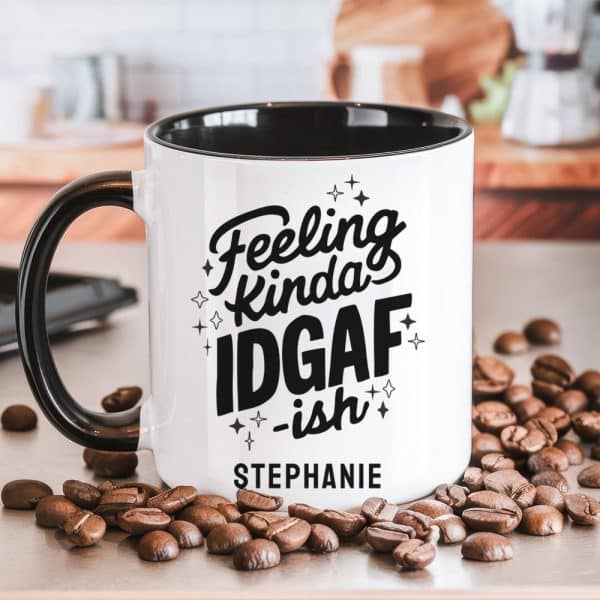 White Coffee Mug With Black Interior And Handle, Featuring The Text Feeling Kinda Idgaf -Ish And The Name Stephanie. Coffee Beans Are Scattered Around The Mug.
