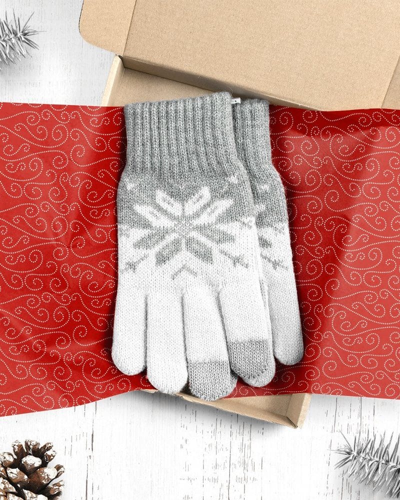 Pair of gray and white knit gloves with snowflake pattern in a gift box.