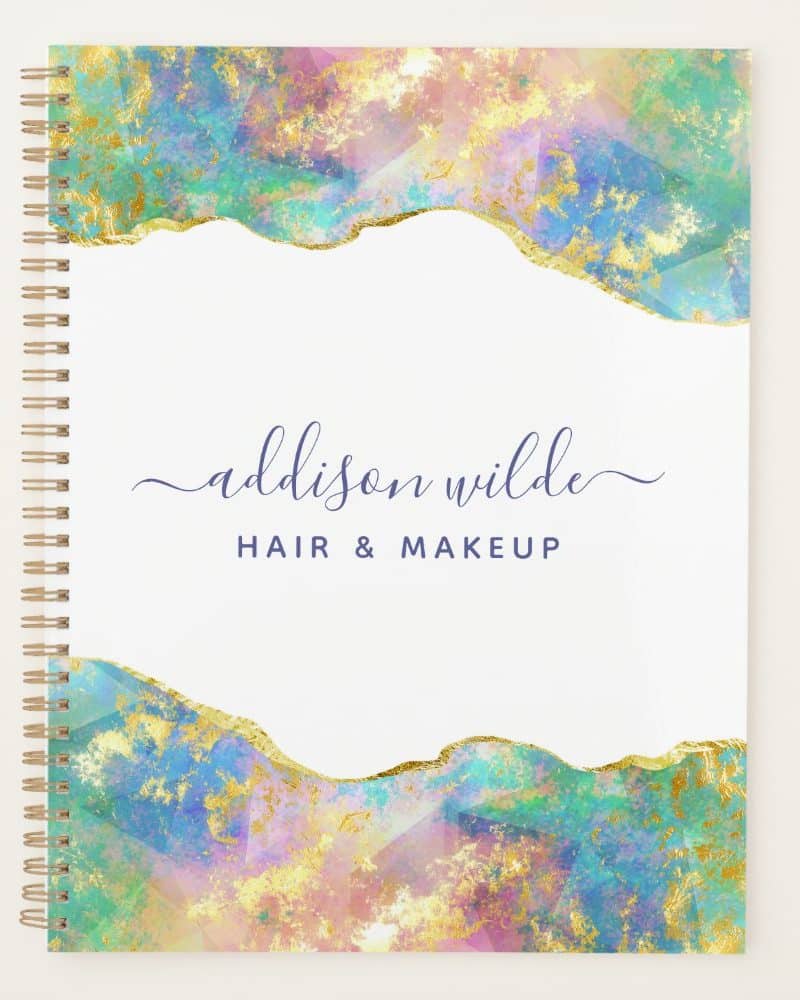 Spiral-bound notebook with a pastel and gold abstract design and Addison Wilde Hair & Makeup written on the cover.