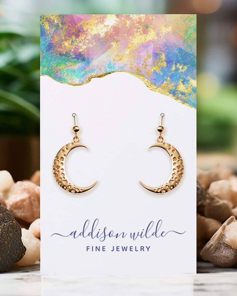 Gold crescent moon earrings displayed on a jewelry card.