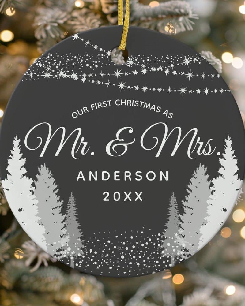 Dark gray round Christmas ornament with silver trees, snowflakes, and stars; text reads "Our First Christmas as Mr. & Mrs. Anderson 20XX".