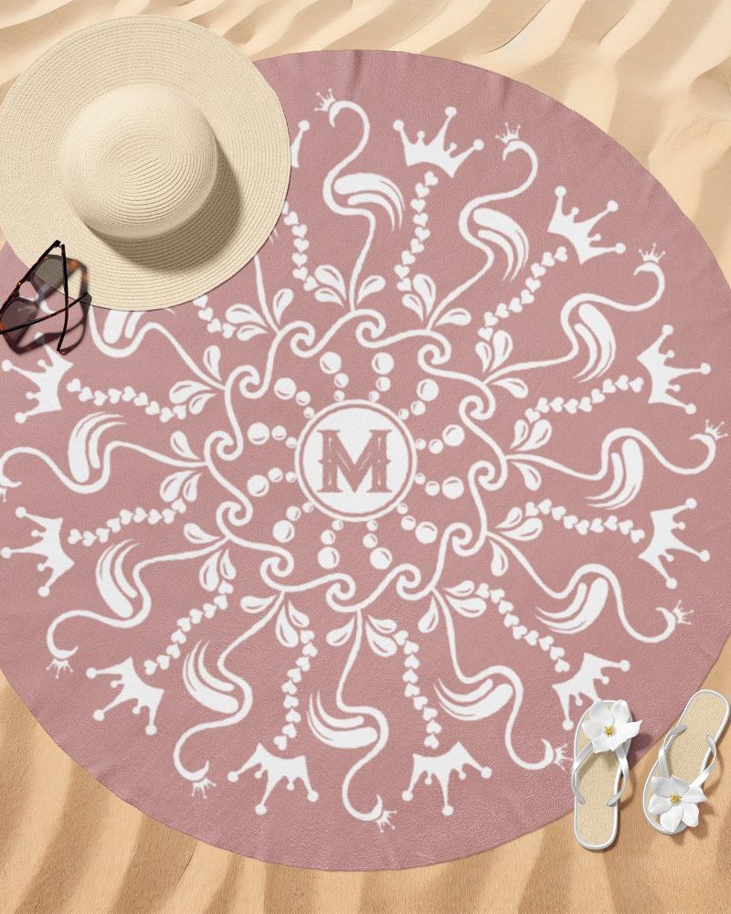 Pink round beach towel with a white mandala design featuring crowns and the initial M.
