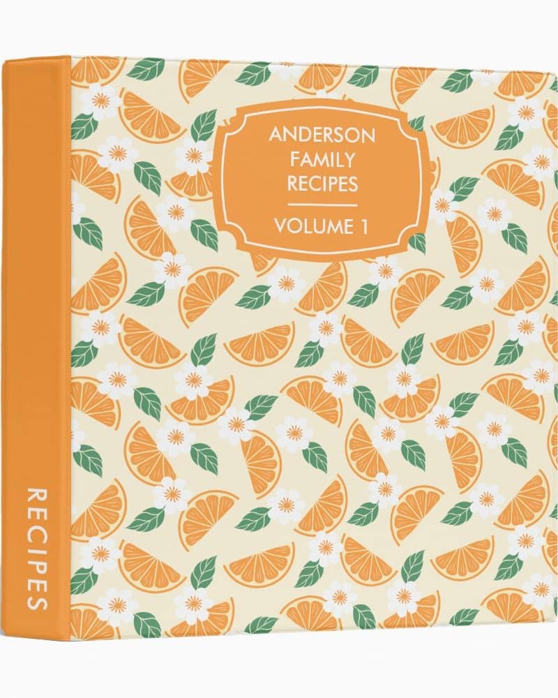 Orange three-ring binder labeled Anderson Family Recipes, Volume 1. The binder features an orange slice and flower pattern.