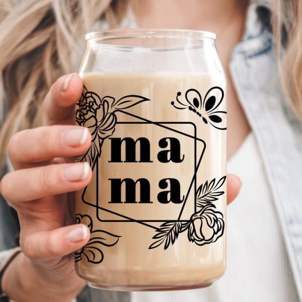 A Hand Holds A Glass With A Beige Beverage. The Glass Features A Design Of The Word Mama, Flowers, And A Butterfly.