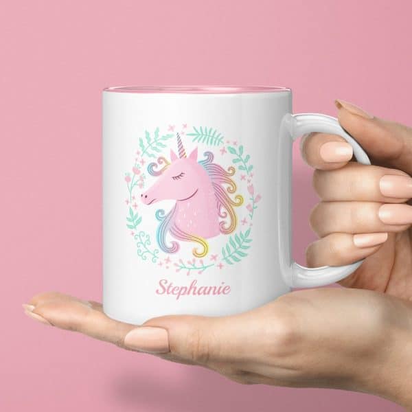 A Hand Holds A White Mug Featuring A Pastel Pink Unicorn Surrounded By Flowers And The Name Stephanie.