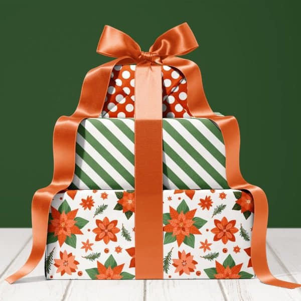 Stack Of Three Festively Wrapped Gifts With A Large Orange Ribbon.