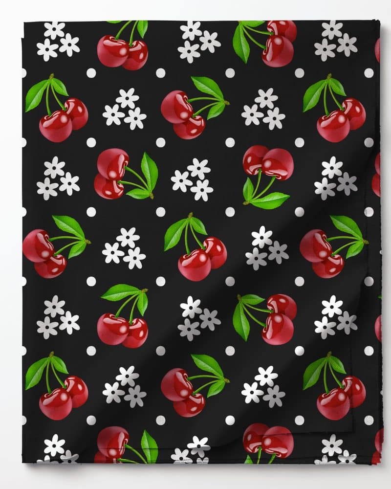 Black fabric with a repeating pattern of red cherries, white flowers, and white polka dots.