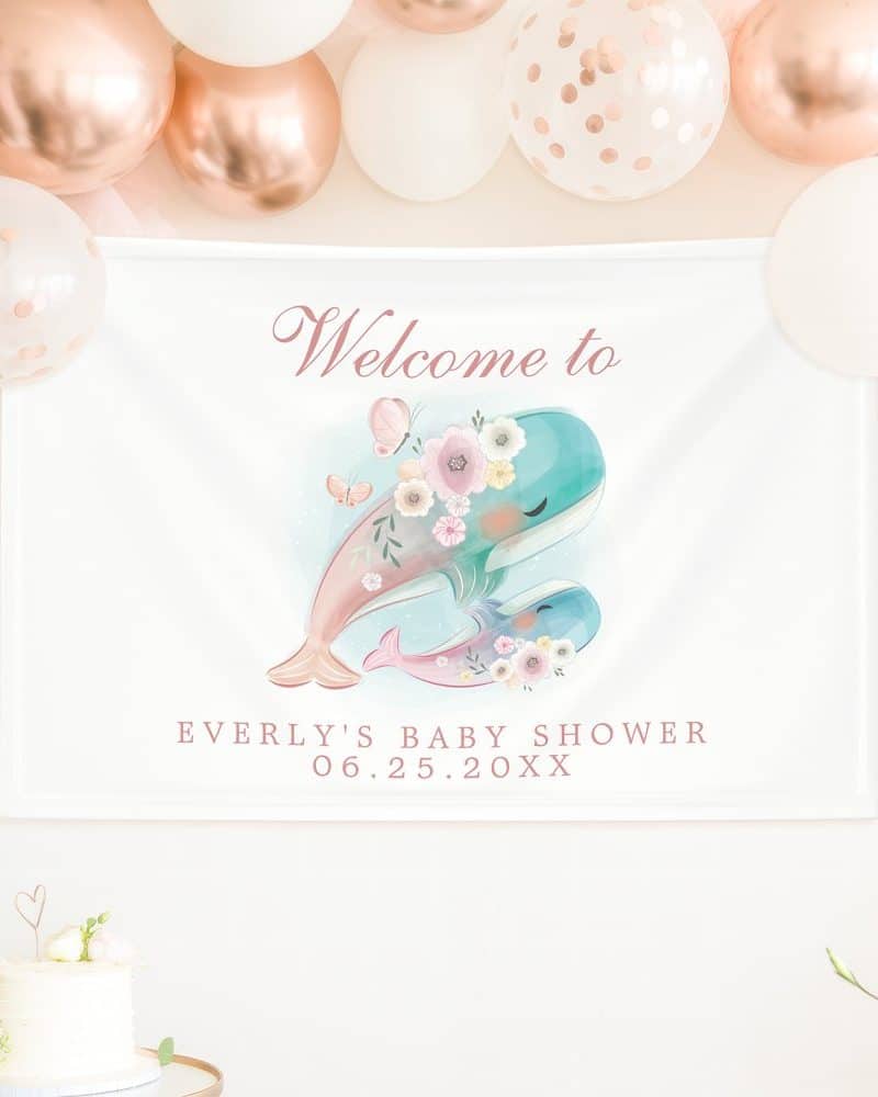 Baby shower banner featuring two whales adorned with flowers, butterflies, and the text Welcome to Everly's Baby Shower with date.