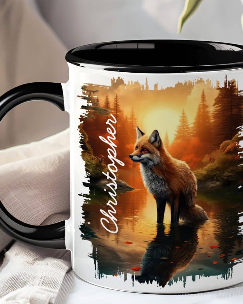 Coffee mug with a black handle and rim, featuring a red fox standing in a tranquil forest scene at sunset, with the name Christopher on the side.