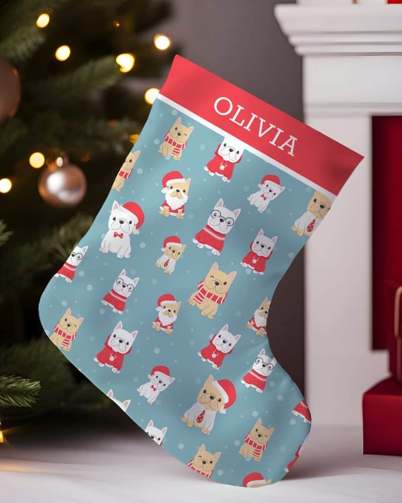 Personalized Christmas stocking with a light blue background and a repeating pattern of French bulldogs in festive attire. The name Olivia is at the top.