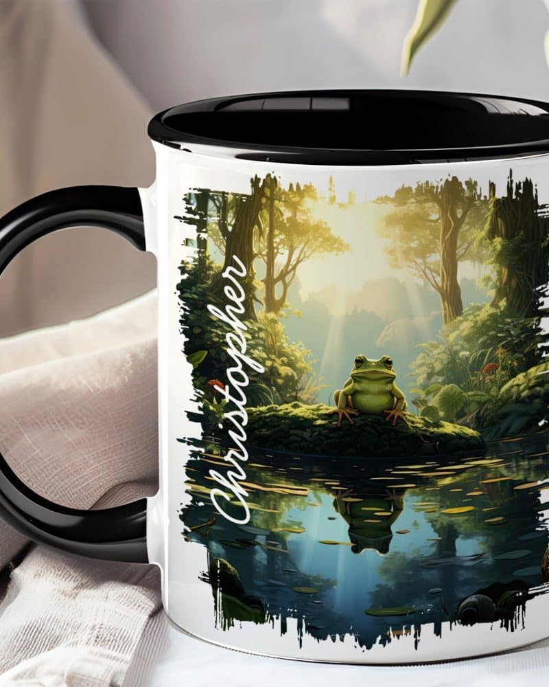 Black-handled mug with a whimsical illustration of a frog sitting on a log by a pond in a sun-dappled forest. The name Christopher is printed on the mug.