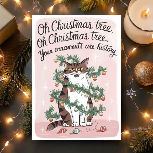 Illustration Of A Tabby Cat Sitting Amidst A Decorated Christmas Tree, With Ornaments Scattered Around It. Text Above Reads, Oh Christmas Tree, Oh Christmas Tree, Your Ornaments Are History.