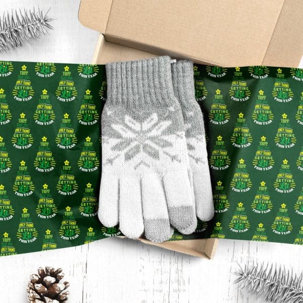 Gray Knit Gloves With A Snowflake Pattern, Presented In A Gift Box Lined With Green Christmas Wrapping Paper.