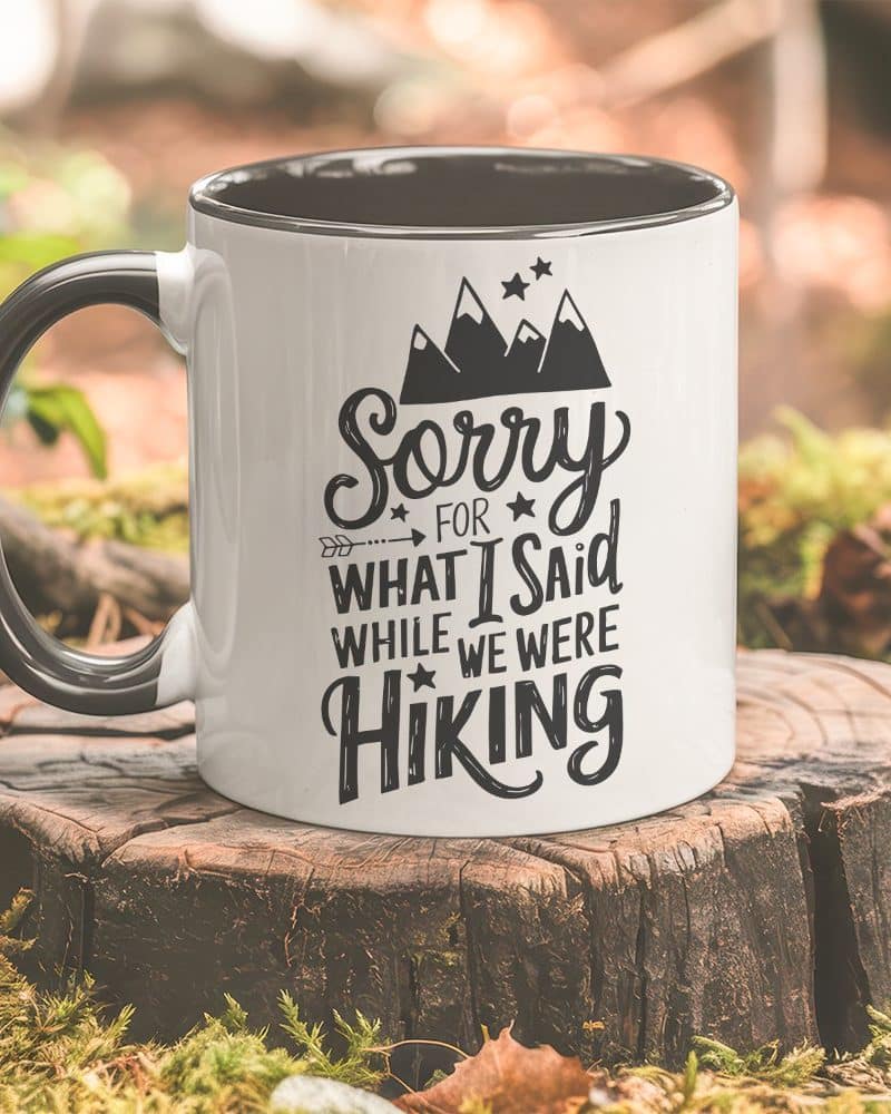 White coffee mug with black lettering that says Sorry for what I said while we were hiking, and a graphic of mountains.