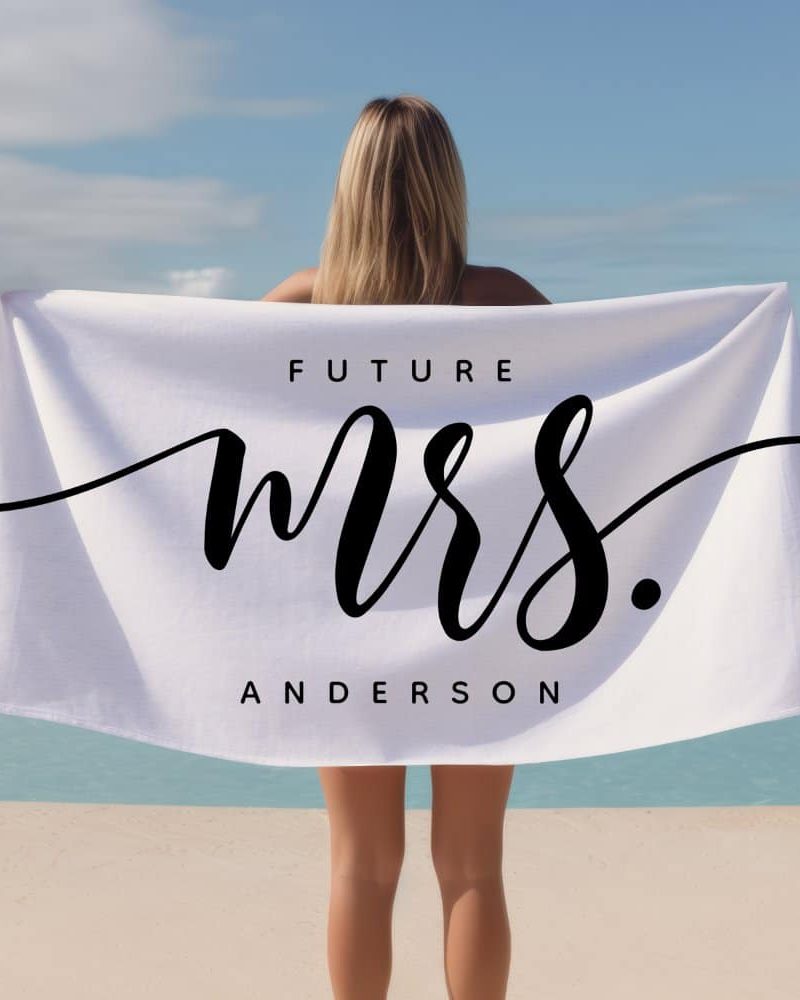 Woman holding a white beach towel that says Future Mrs. Anderson.