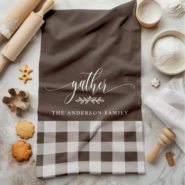 Brown Kitchen Towel With White Script Reading Gather, The Anderson Family, And A Brown And White Gingham Bottom Border.