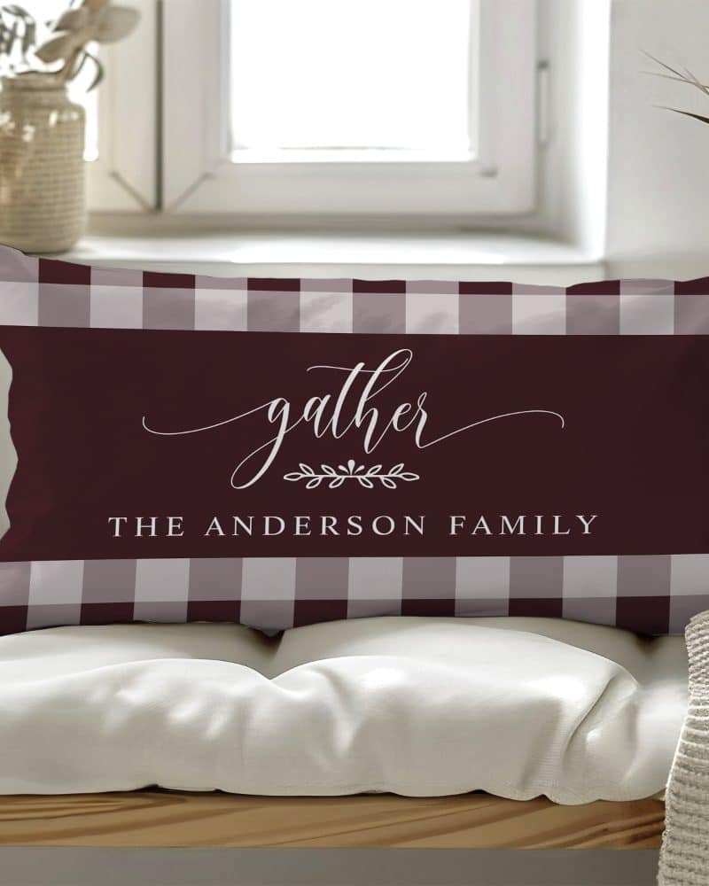 Rectangular burgundy and gray gingham pillow with the word gather and the Anderson family name.