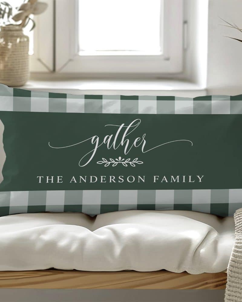 Rectangular pillow with a green and white gingham pattern, featuring the word Gather in elegant script, a small floral design, and the text The Anderson Family.