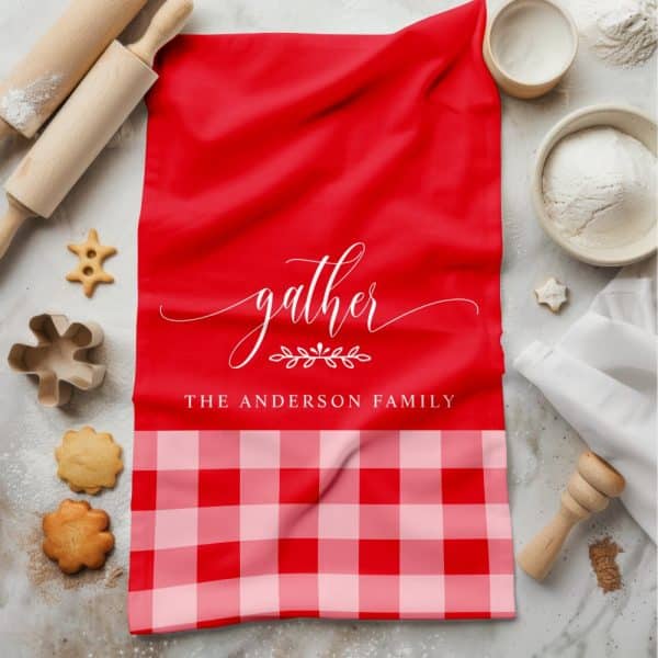 Red Kitchen Towel With The Word Gather In A Script Font And The Anderson Family Name. The Bottom Features A Red And Pink Gingham Pattern.