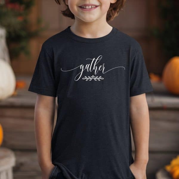 Child Wearing A Dark Gray T-Shirt With The Word Gather In White Script Lettering And A Small Leaf Design Underneath.