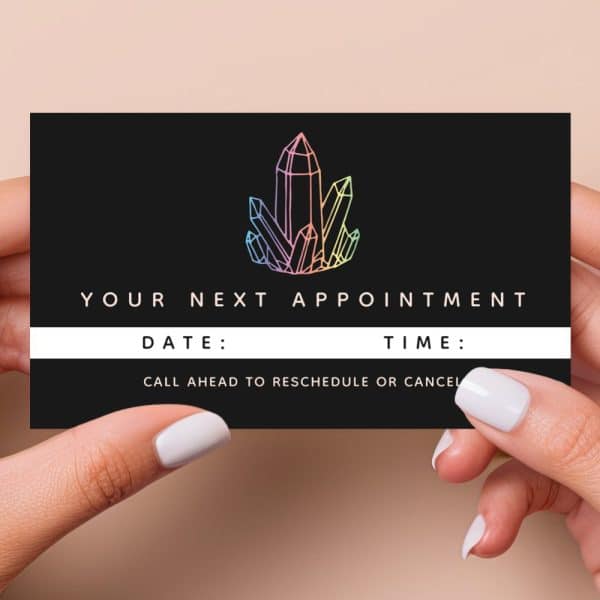 Two Hands Hold A Black Appointment Card Featuring A Pastel Crystal Illustration. The Card Displays The Text &Quot;Your Next Appointment,&Quot; With Lines For Date And Time. A Note Indicates To Call Ahead To Reschedule Or Cancel.