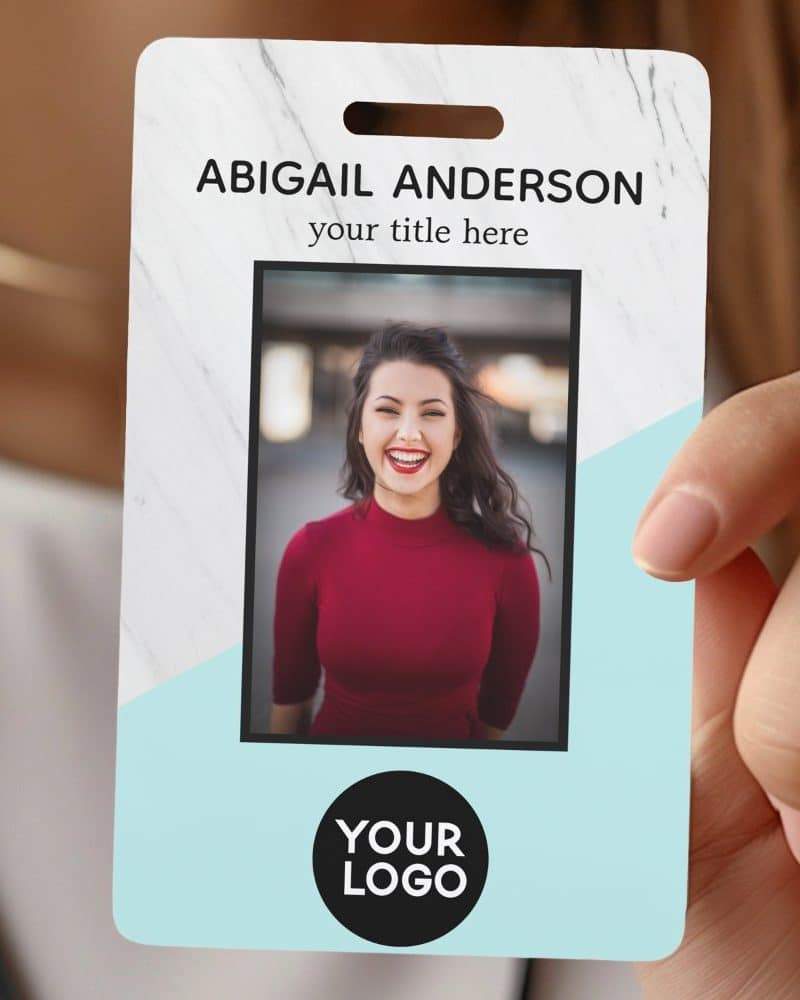 A hand holds a marble and light blue employee ID badge with a photo of Abigail Anderson.