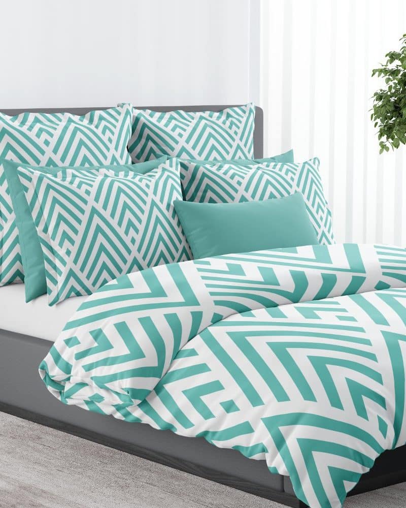 Teal and white geometric patterned duvet cover and pillow set on a gray bed.