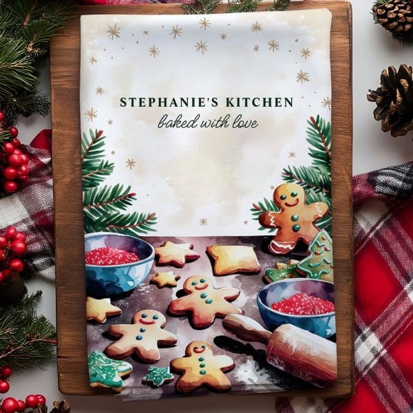A Kitchen Tea Towel Featuring Watercolor Illustrations Of Gingerbread Men And Cookies, Along With The Text Stephanie'S Kitchen Baked With Love.