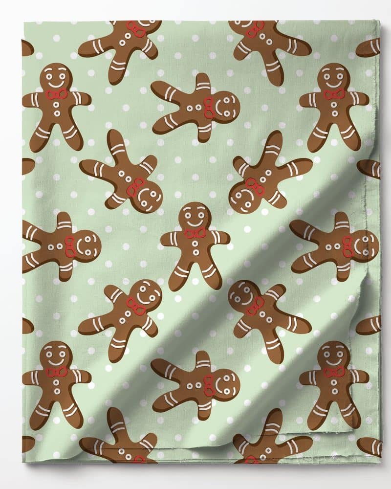 A light green fabric with a repeating pattern of gingerbread men wearing red bow ties.