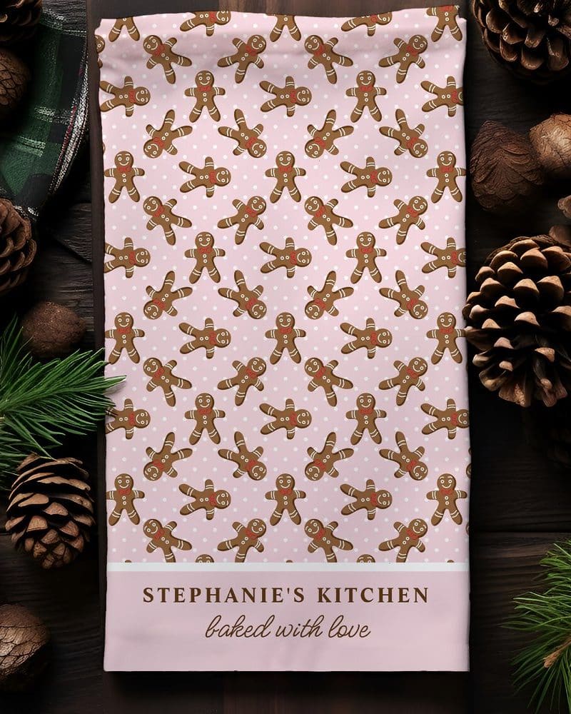 Pink tea towel with a repeating pattern of gingerbread men, personalized with Stephanie's Kitchen baked with love.