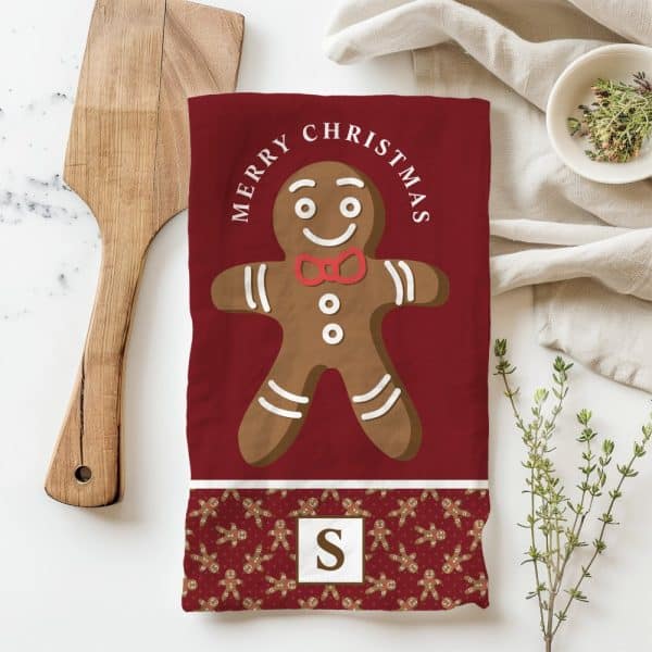 Red Christmas Tea Towel Featuring A Large Gingerbread Man And The Text Merry Christmas.