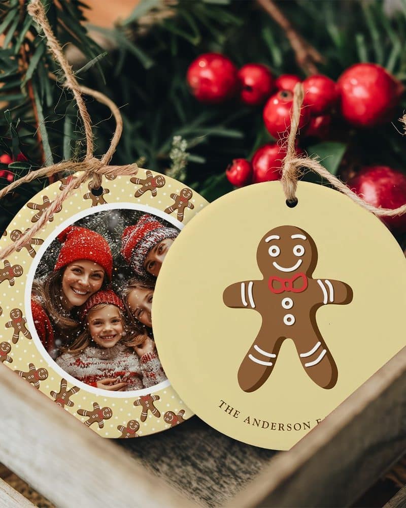 Two round Christmas ornaments; one features a family photo surrounded by gingerbread men, the other shows a single gingerbread man with a family name.