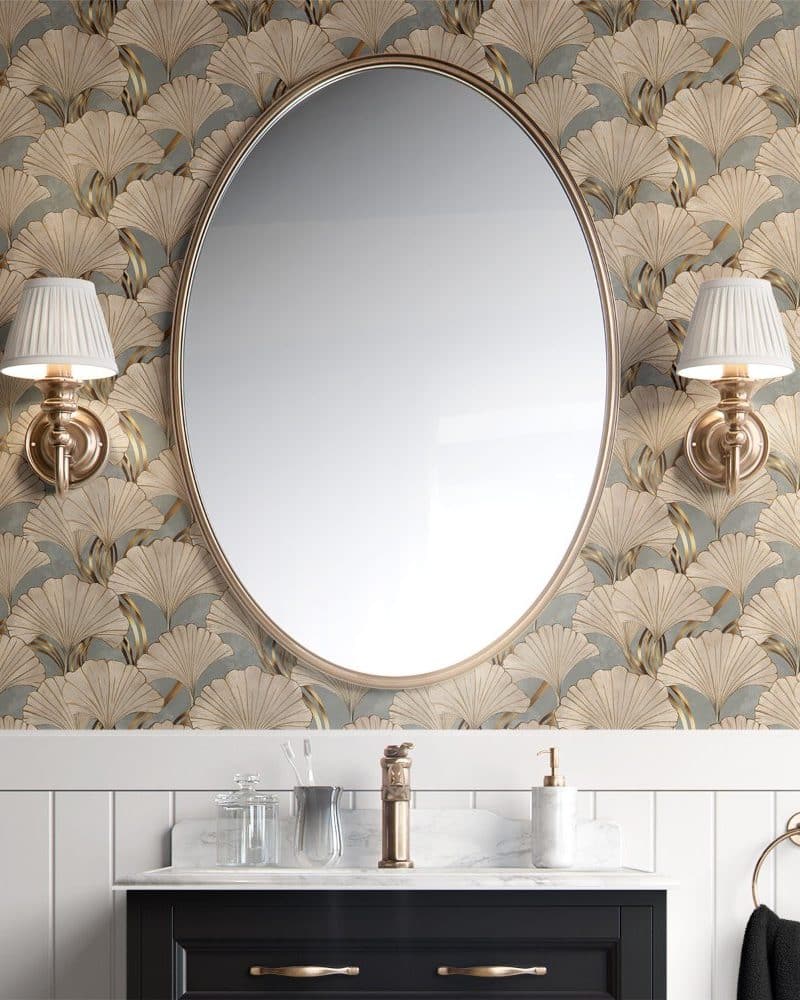 Oval mirror flanked by wall-mounted lights, above a bathroom vanity with ginkgo leaf patterned wallpaper.