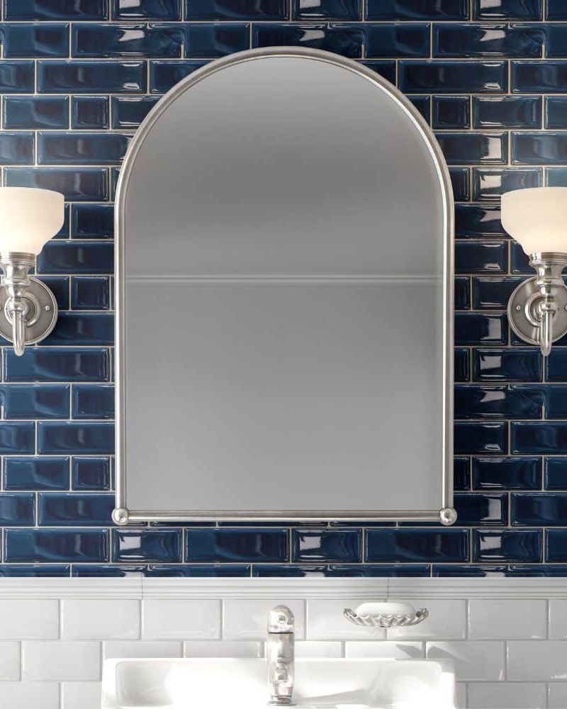 Arch-shaped mirror flanked by wall-mounted lights above a bathroom sink.