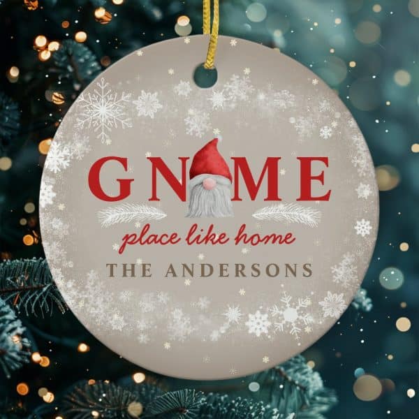 Round Christmas Ornament Featuring A Gnome In The Center Of The Word Gnome, With The Text Place Like Home And The Andersons Family Name Below. Snowflakes Decorate The Background.