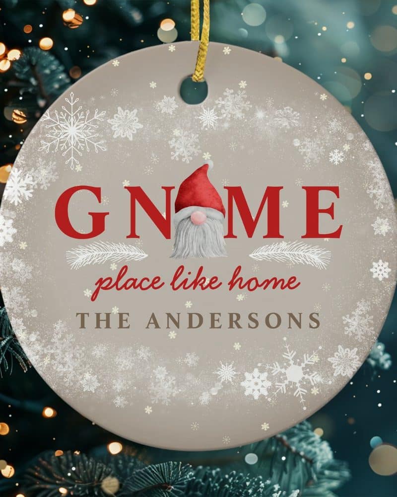 Round Christmas ornament featuring a gnome in the center of the word GNOME, with the text place like home and the Andersons family name below. Snowflakes decorate the background.