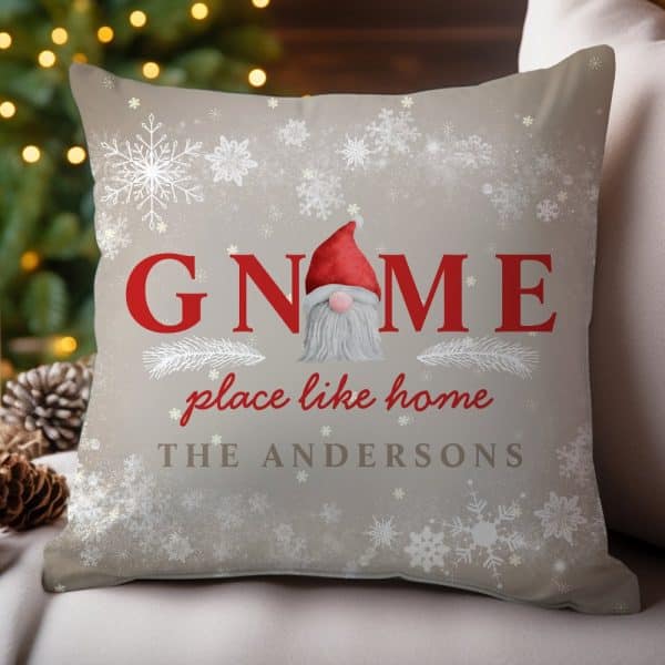 Tan Christmas Pillow With A Red-Hatted Gnome In The Center Of The Word Gnome. The Words Place Like Home And The Andersons Family Name Are Also On The Pillow, Surrounded By Snowflakes.