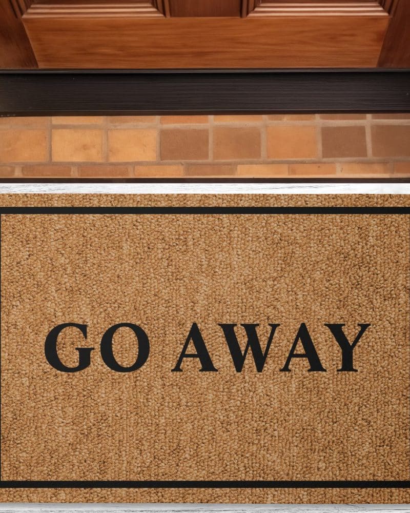 A tan welcome mat with black border and the words Go Away in black lettering.