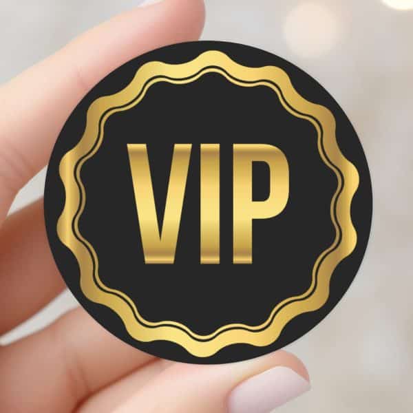 Hand Holding A Black And Gold Vip Sticker.