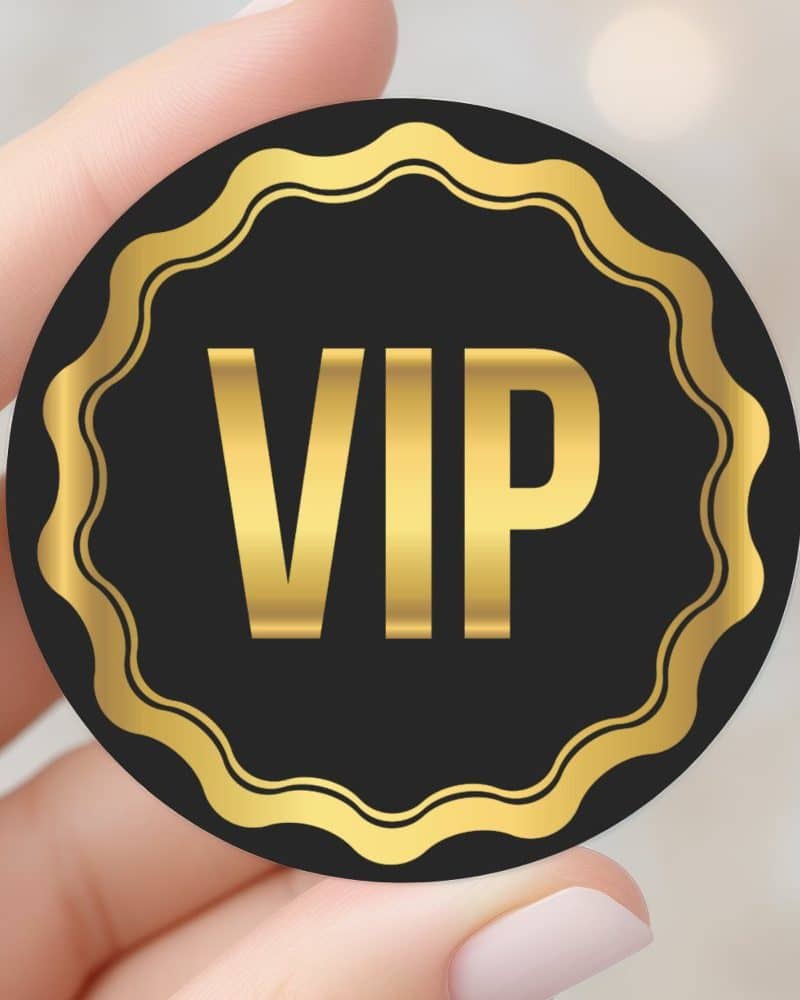 Hand holding a black and gold VIP sticker.
